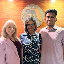 Rohan Shirur standing beside two women wearing a pink polo shirt